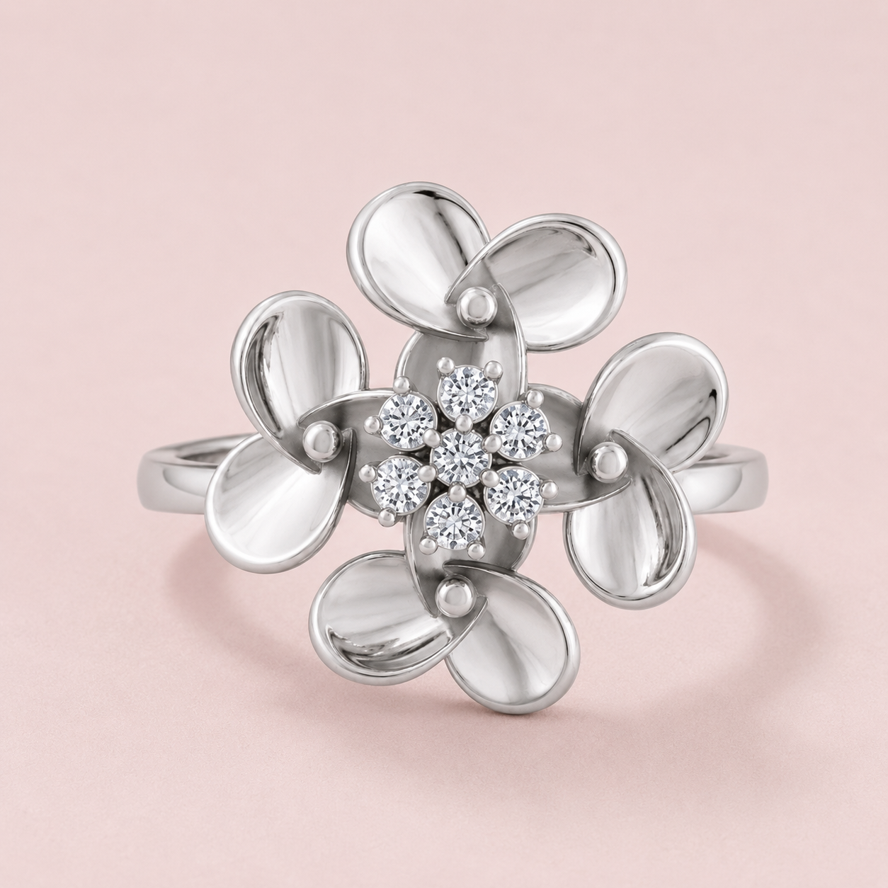 A 925 silver flower ring with six polished petals and a central cluster of clear diamonds, set against a soft pink background.