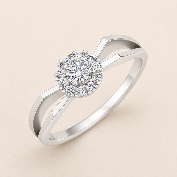 A silver-toned halo ring with a round-cut center stone and a surrounding halo of smaller stones, shown on a soft beige background.
