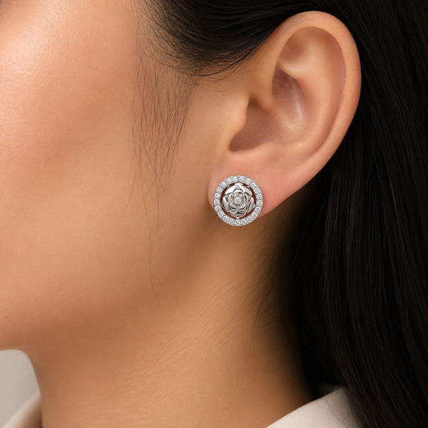 A close-up of a person's ear wearing a rose-shaped stud diamond earring with a halo of small clear diamond .