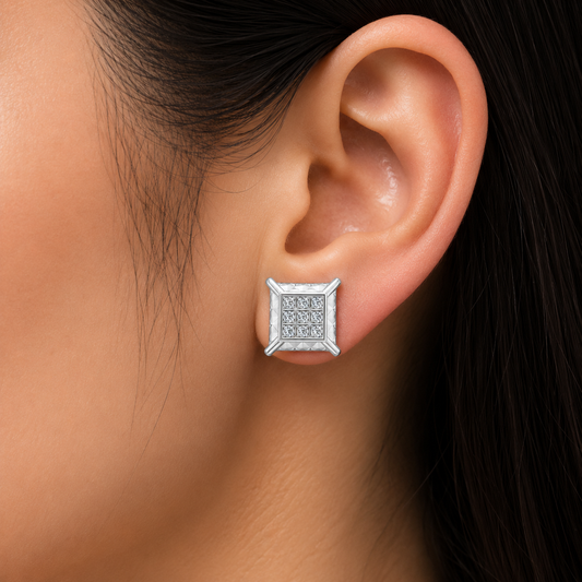 A close-up of a person's ear wearing a square stud diamond earring with a silver-toned border and a pavé-set center, likely set with clear diamonds.