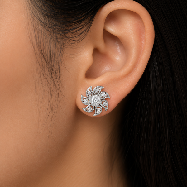 A close-up of a woman's ear wearing a silver-toned flower-shaped stud diamond earring set with clear diamonds .