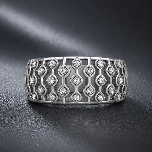 A silver-toned wide band ring featuring an intricate openwork geometric trellis pattern set with small clear round-cut stones, photographed on a dark textured surface.