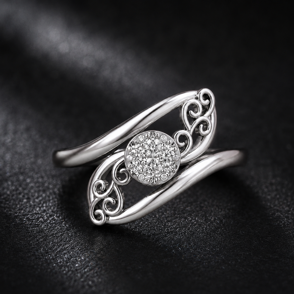 A silver-toned wave-shaped ring with an intricate filigree design and a round pavé center stone, displayed on a textured black background.
