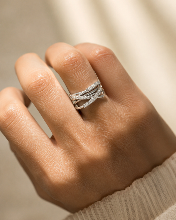 A close-up of a hand wearing a silver ring with a pavé-set diamond band, styled with a matching silver wrap ring.
