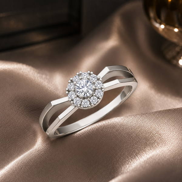 A silver ring with a round halo cluster of clear gemstones, resting on draped champagne-colored satin fabric.
